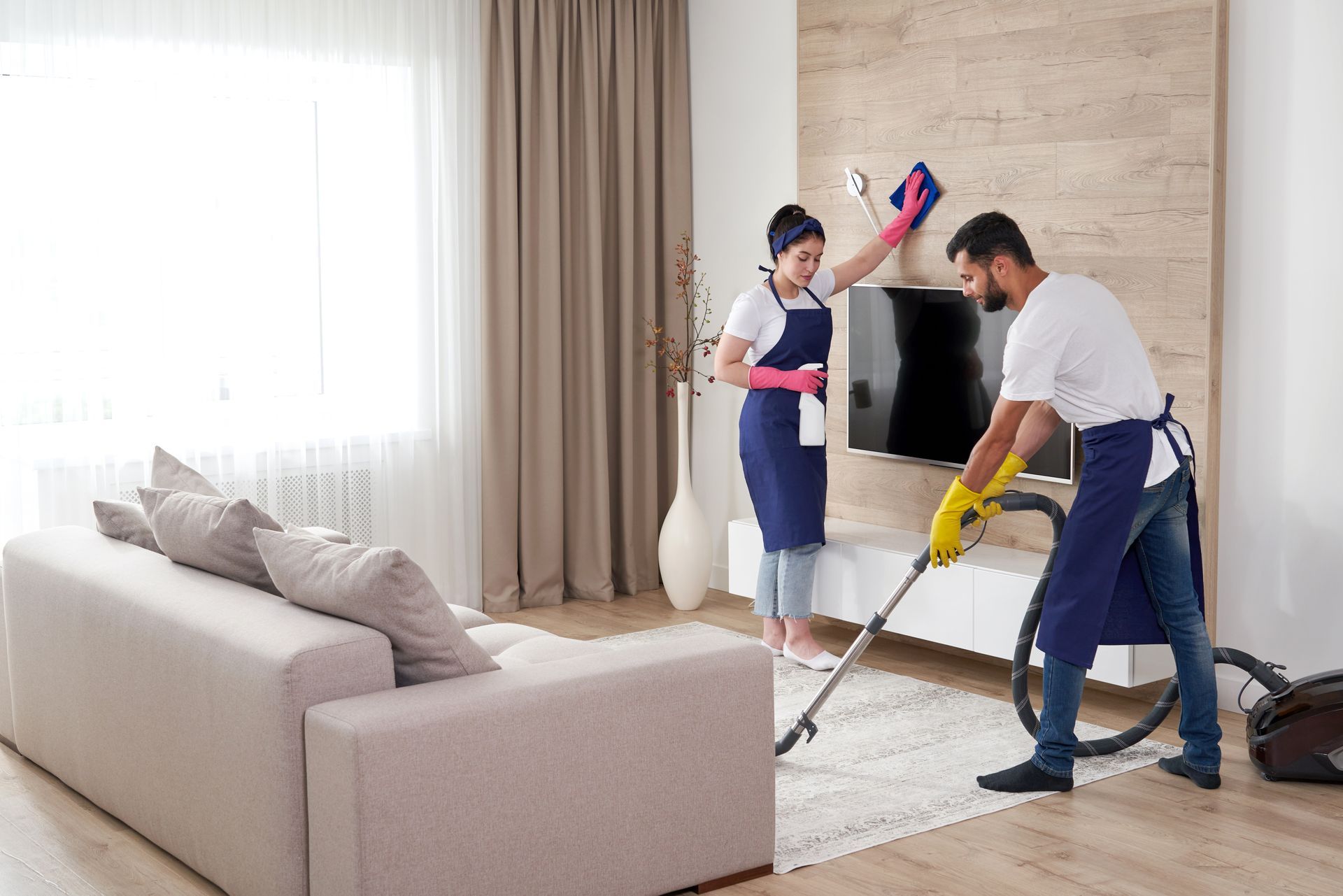 A man is cleaning the floor of an office with a vacuum cleaner.