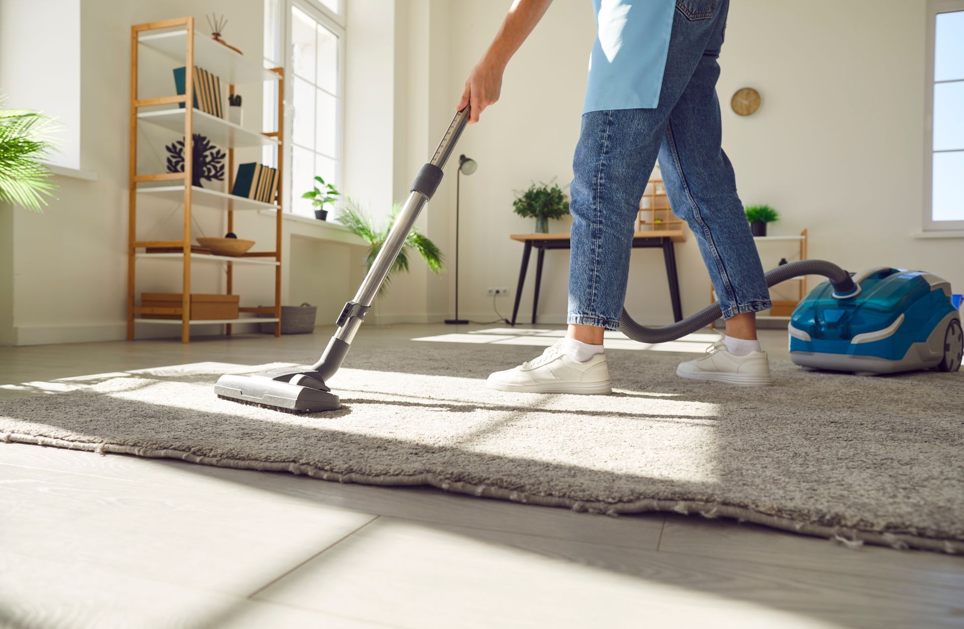 A woman is cleaning the floor with a mop in a living room.