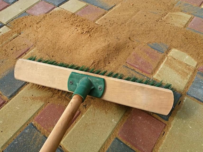 A Broom with Green Bristles Is Laying on A Brick Floor — Australian Sandstone Products In Toowoomba, QLD