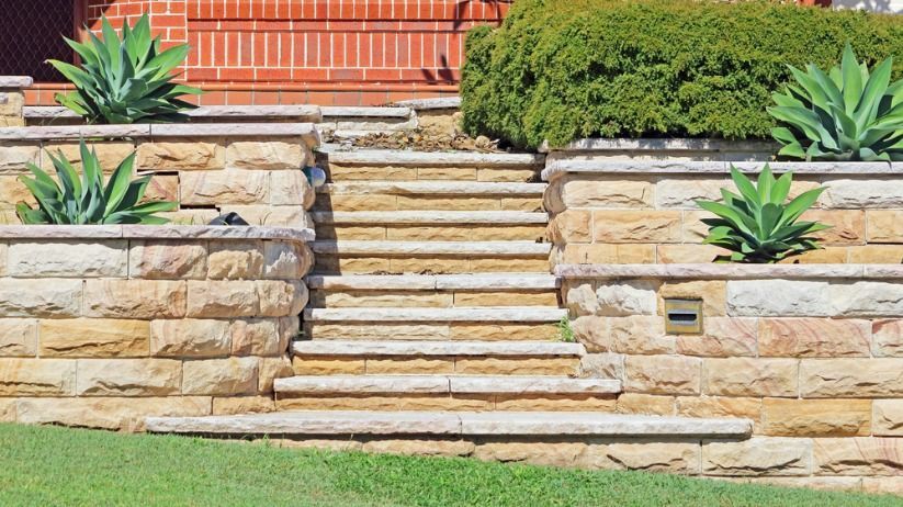 Stone Wall With Stairs Leading Up to a Brick House — Australian Sandstone Products In Gatton, QLD