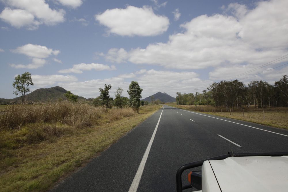 A Car Is Driving Down A Country Road With Mountains In The Background — Australian Sandstone Products In Dalby, QLD