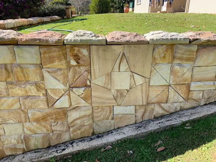 A Stone Wall With A Star Carved Into It Is In Front Of A House — Australian Sandstone Products In Helidon, QLD