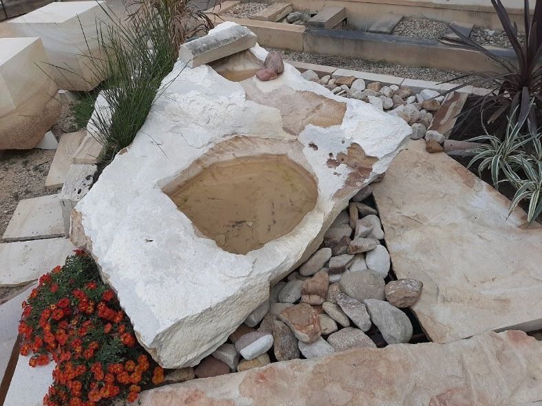 Large Rock With a Hole in It is Surrounded by Rocks and Flowers — Australian Sandstone Products In Helidon, QLD