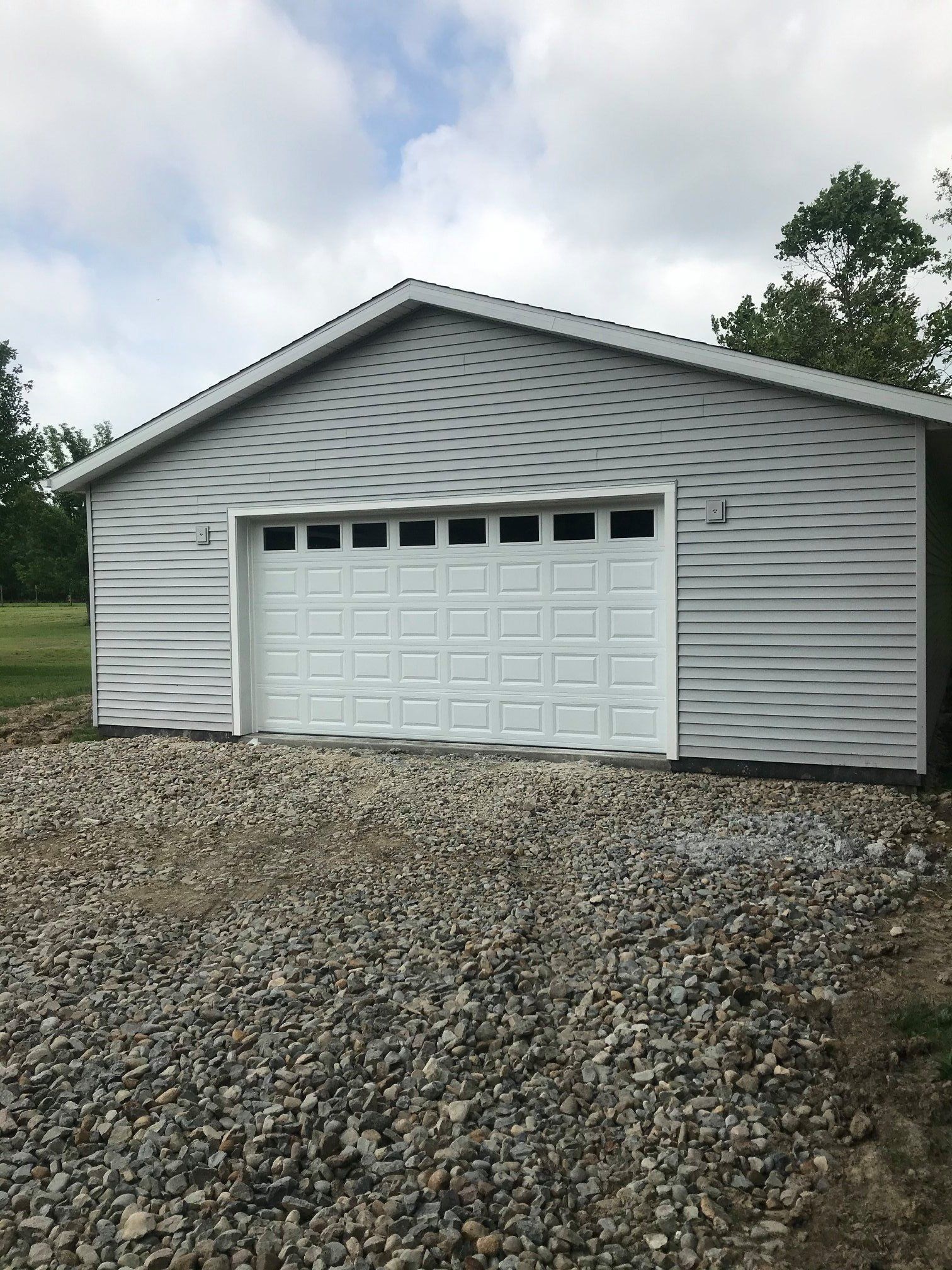 A garage with a white door is sitting on top of a gravel driveway.