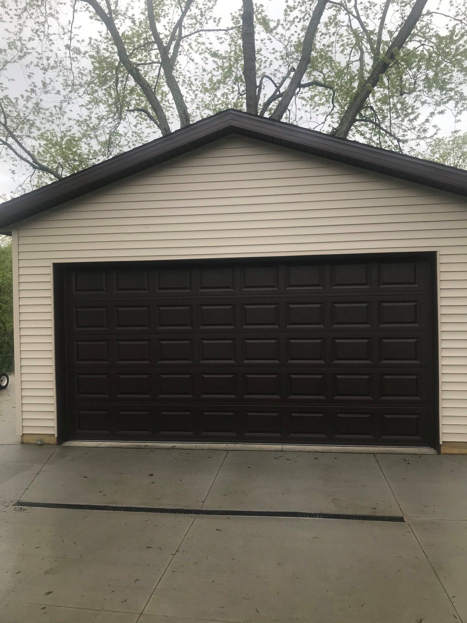 A large garage with a black door and white siding.