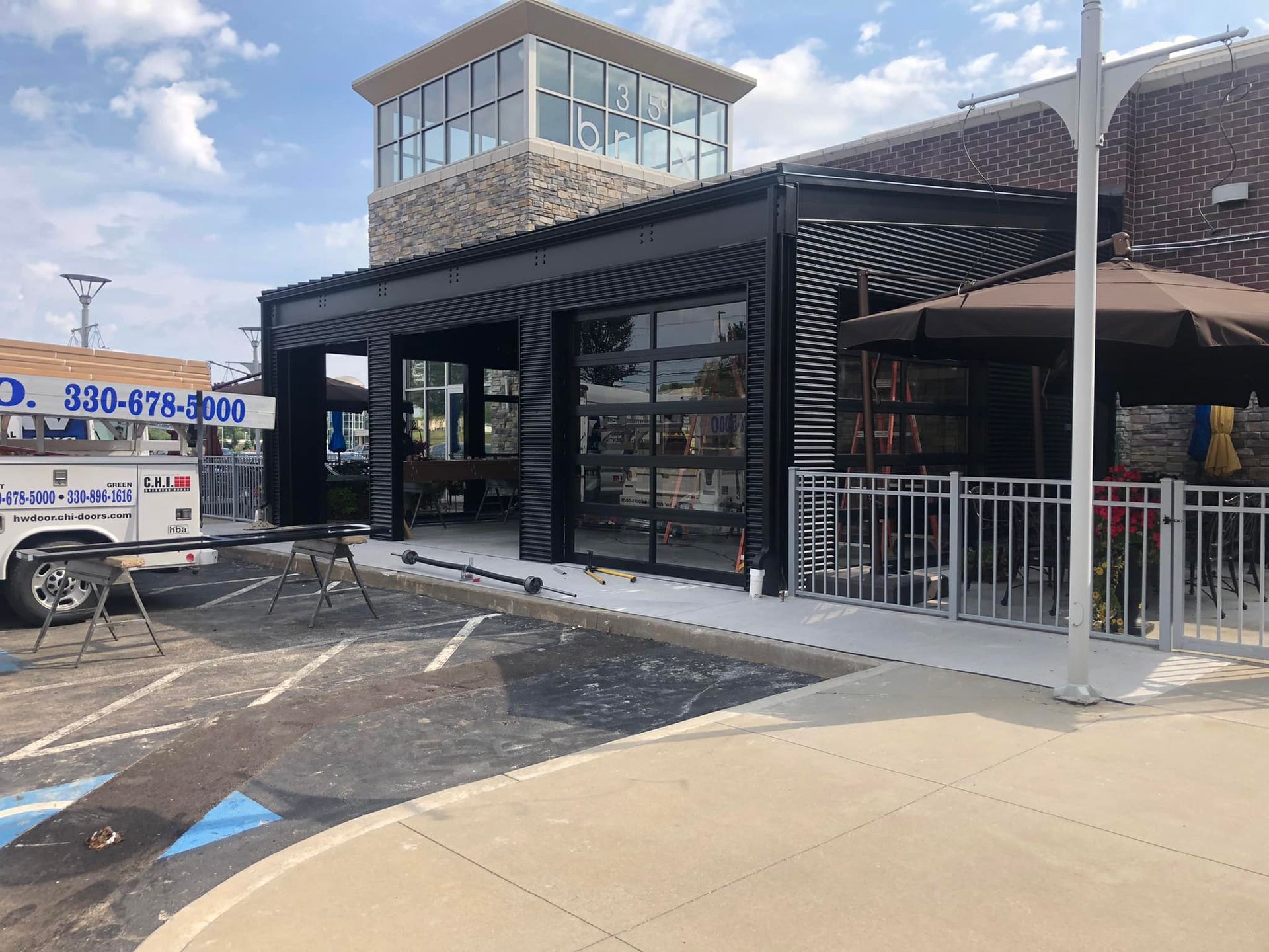 A white truck is parked in front of a building with a phone number on it