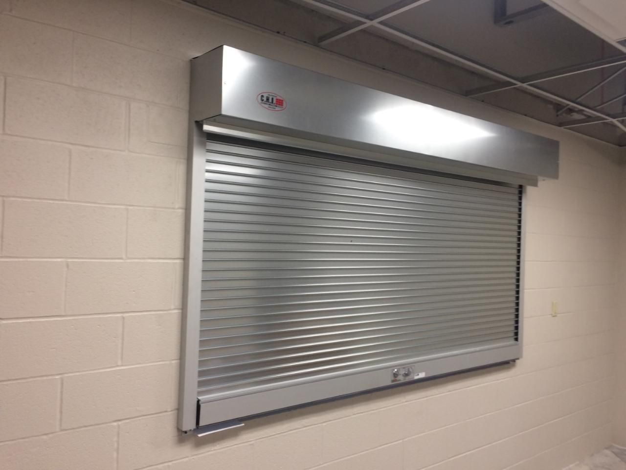 A stainless steel roller shutter is hanging on a brick wall