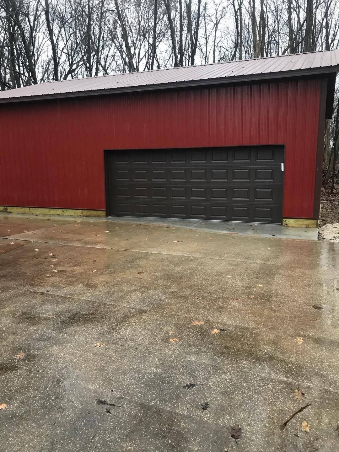 A red garage with a black garage door and a concrete driveway.