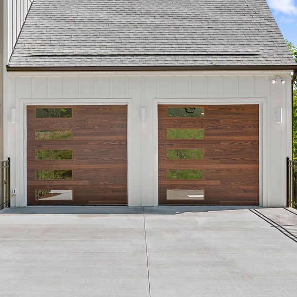 A white house with a wooden garage door and a concrete driveway.