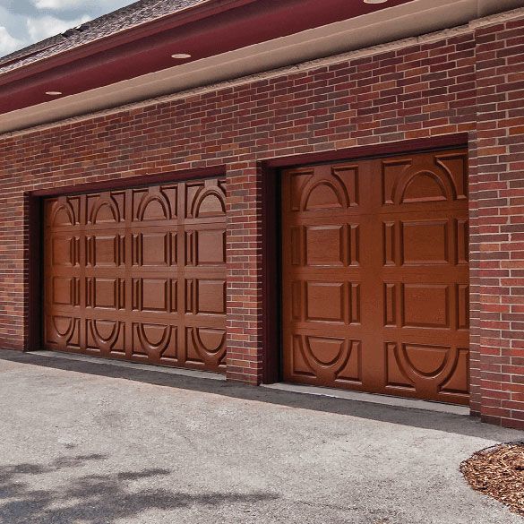 Two brown garage doors on a brick building