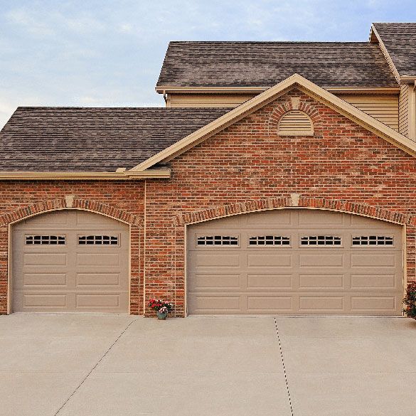 A large brick house with three tan garage doors