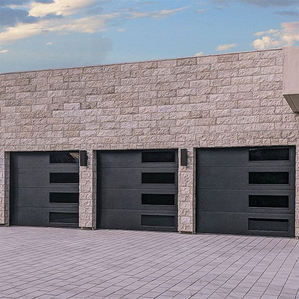 A brick building with three black garage doors