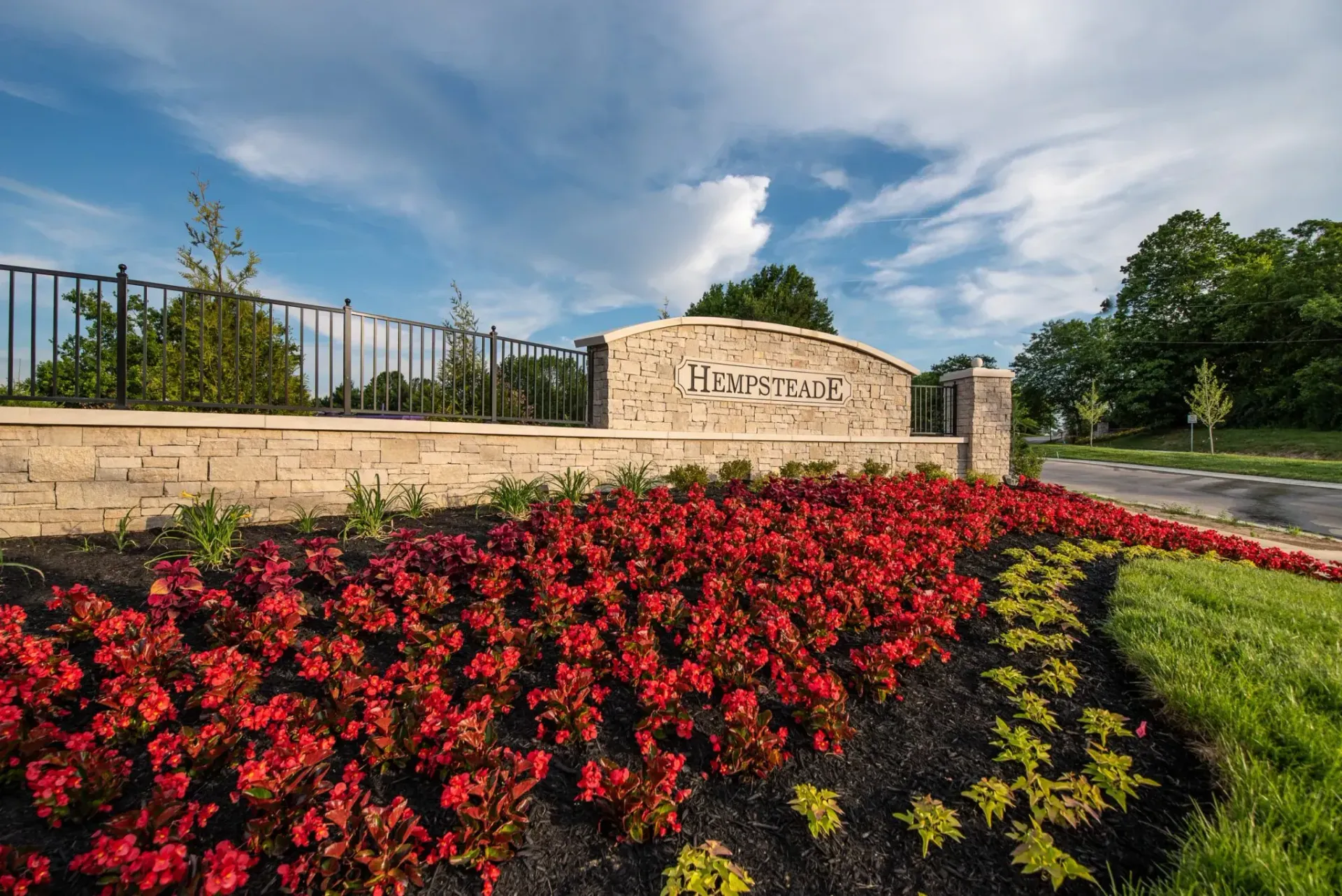 A sign that says liberty is surrounded by flowers and grass.