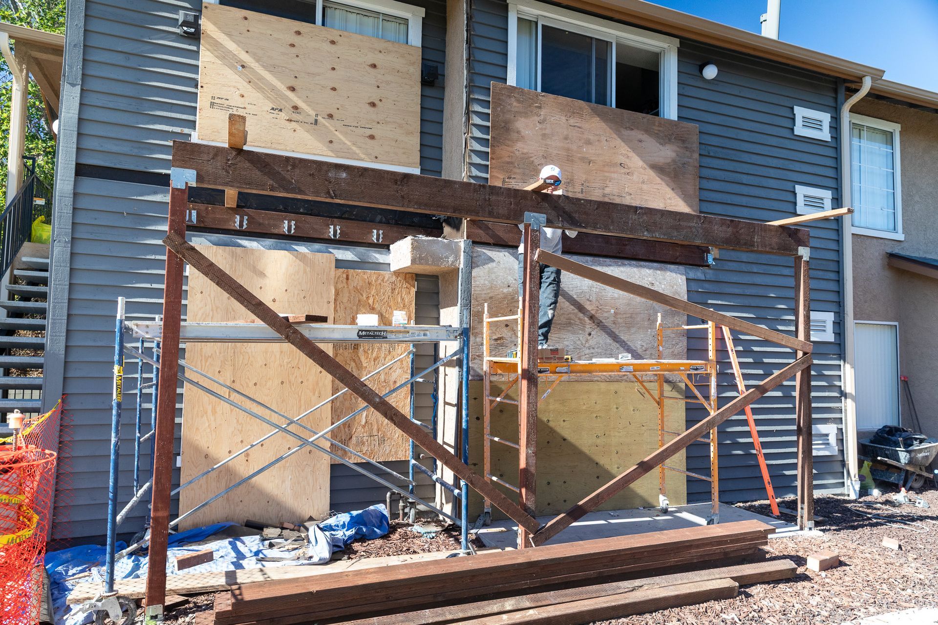 Exterior of a building under construction, with plywood boards, scaffolding, and steel beams.