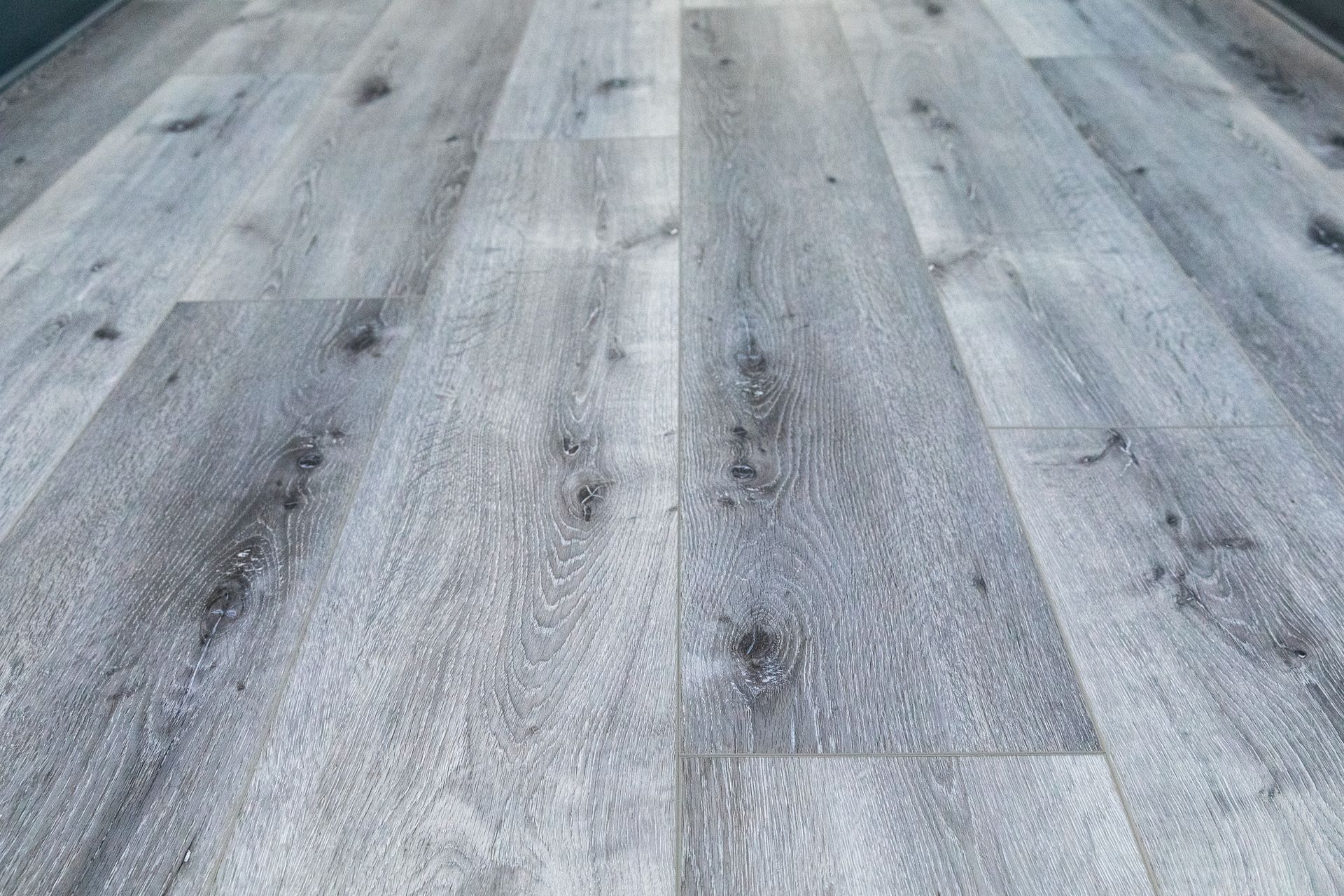 Gray wood-look flooring with dark knots, planks arranged lengthwise.