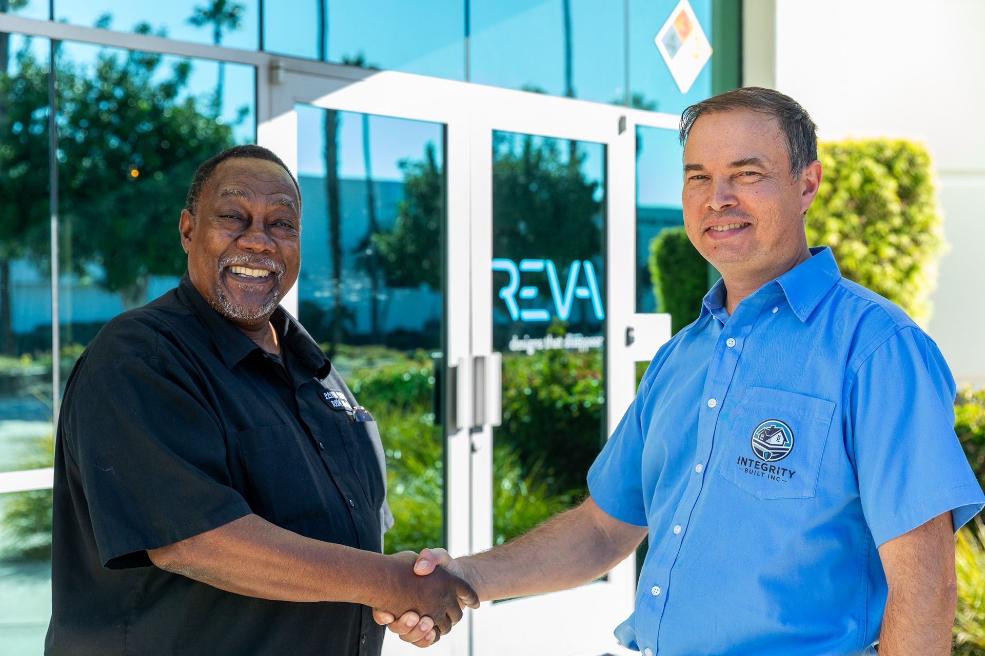 Two men shaking hands in front of a building with the word