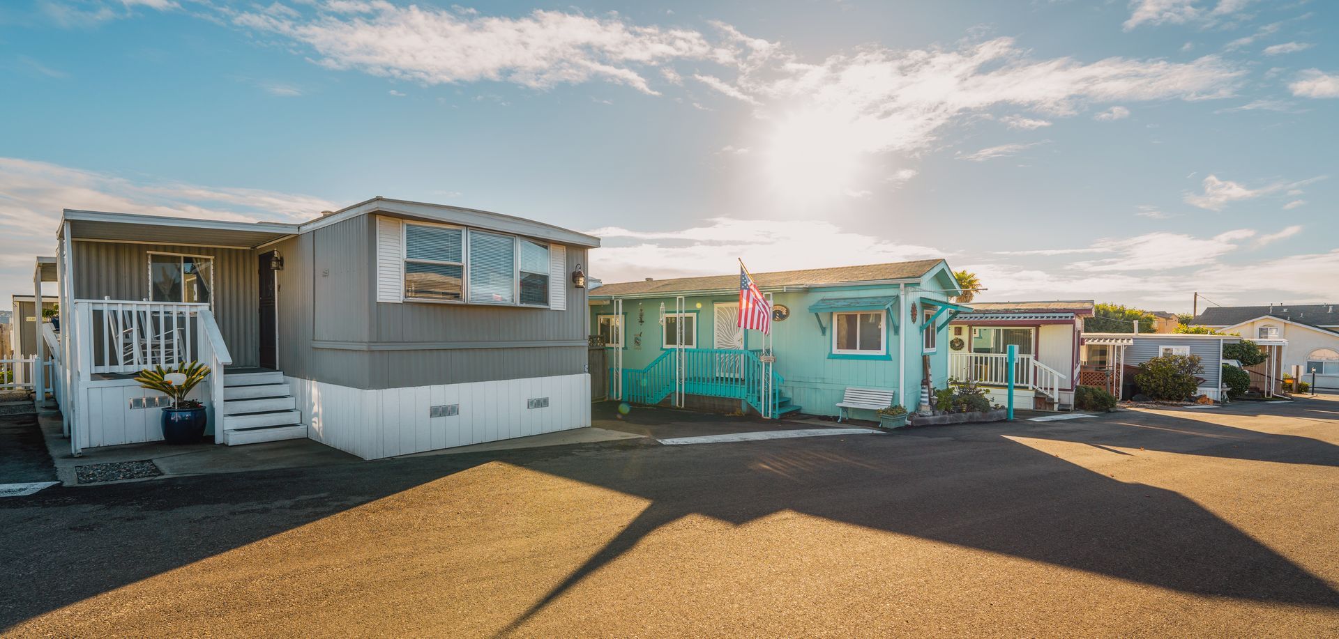 Mobile homes on a sunny day with blue sky. A gray one and a turquoise one in the center.
