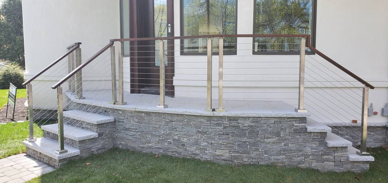 Stone steps with stainless steel railing leading to a doorway.