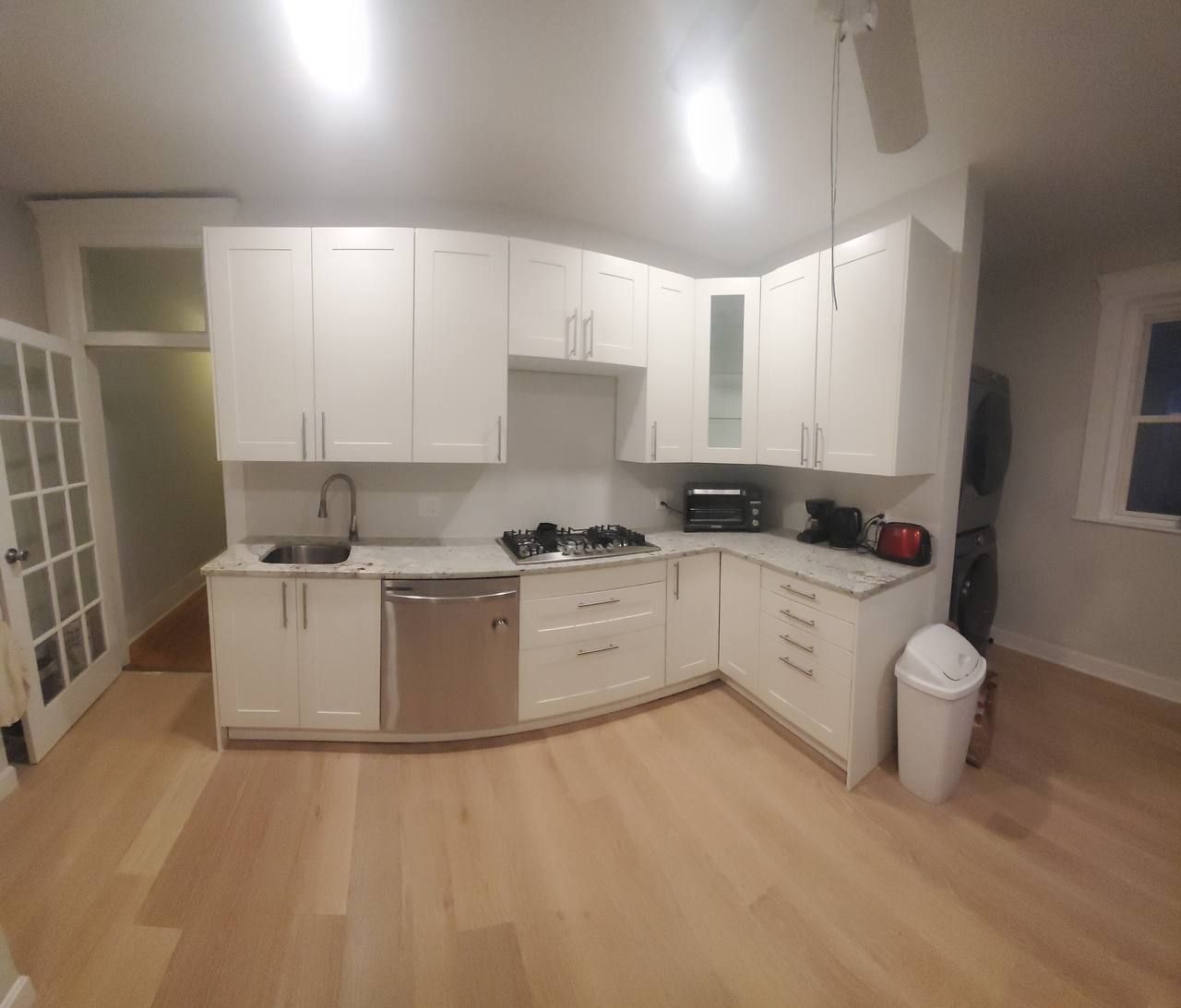 White kitchen with light wood floors, cabinets, and appliances.