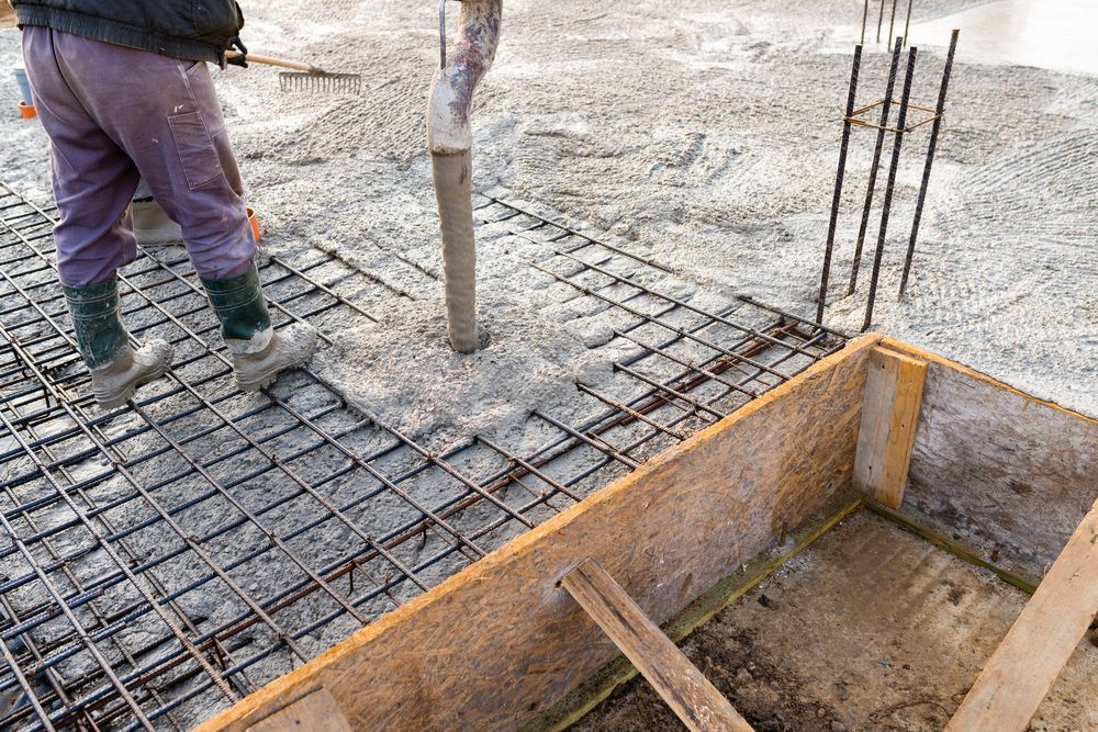A man is pouring concrete into a hole in the ground.