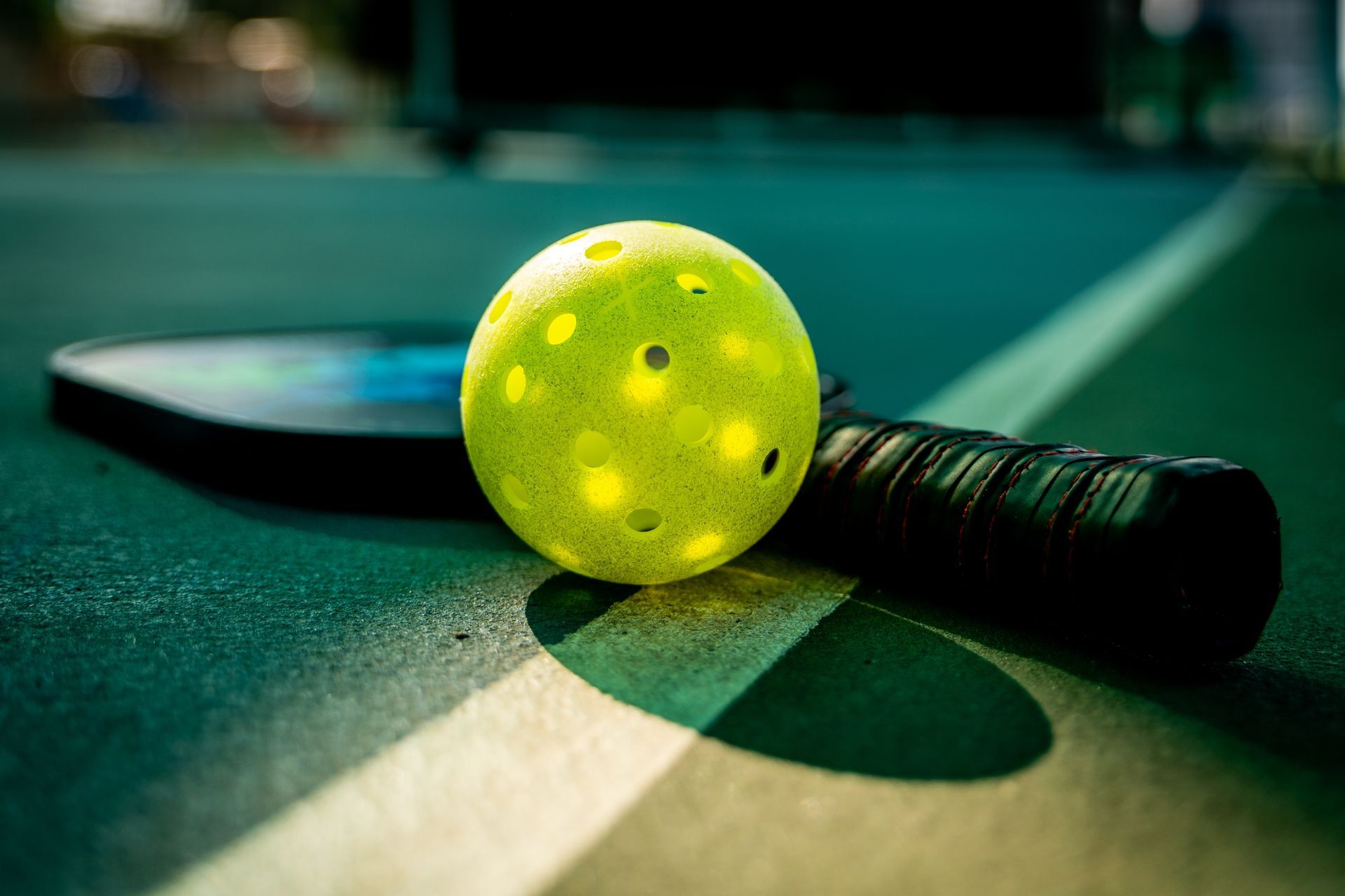 A yellow tennis ball is sitting on top of a paddle on a tennis court.