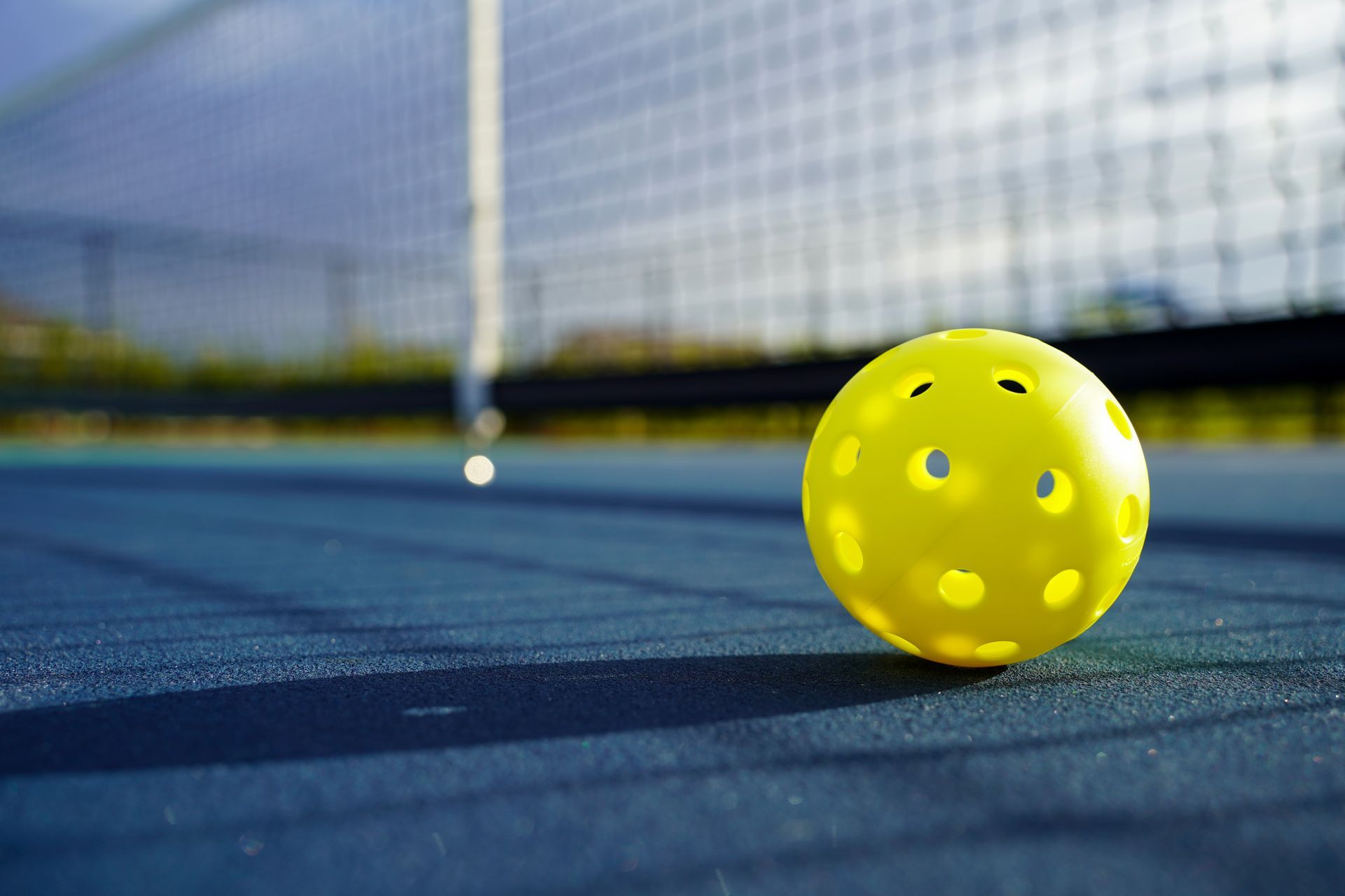A yellow ball is sitting on top of a tennis court.