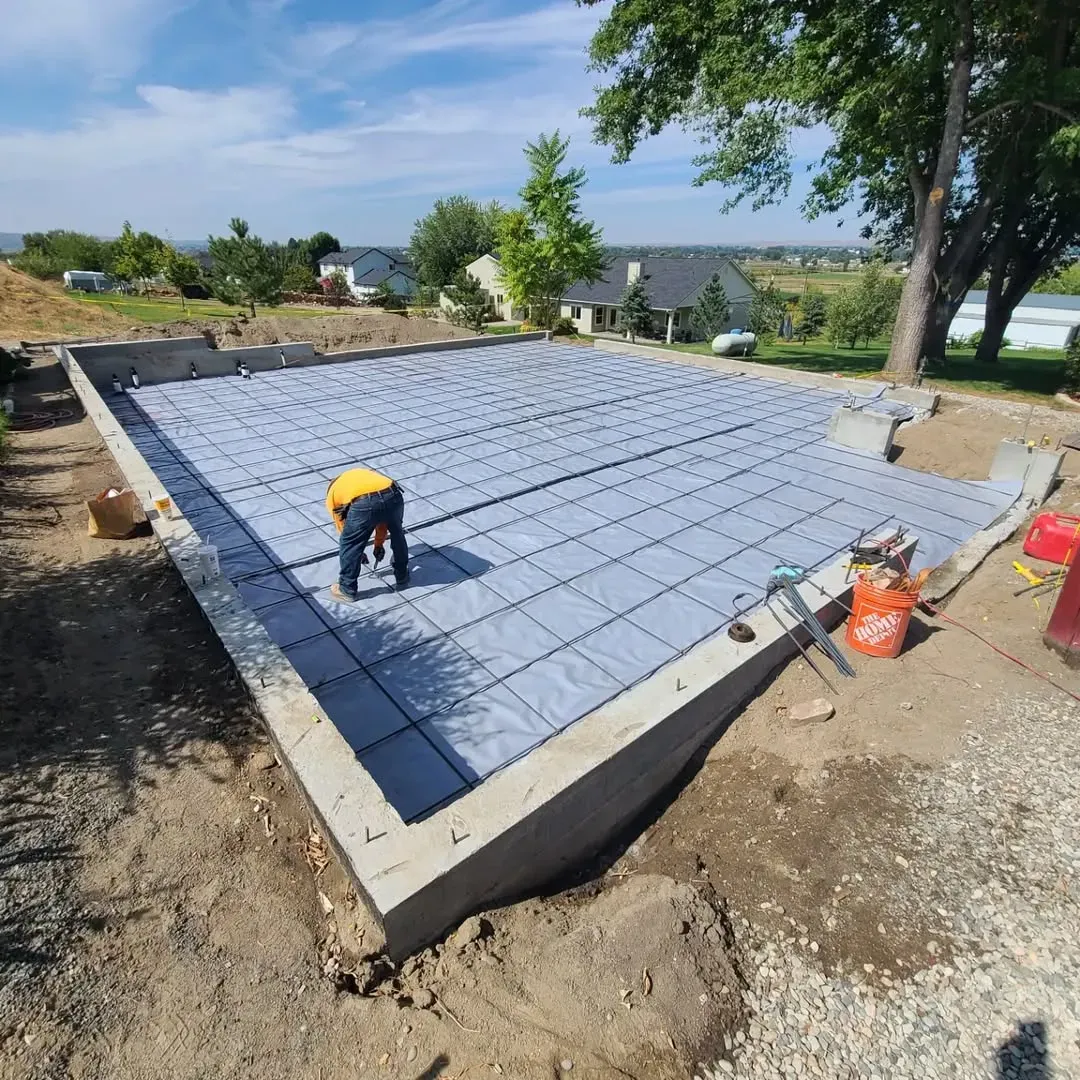 A man is working on a concrete base for a house.