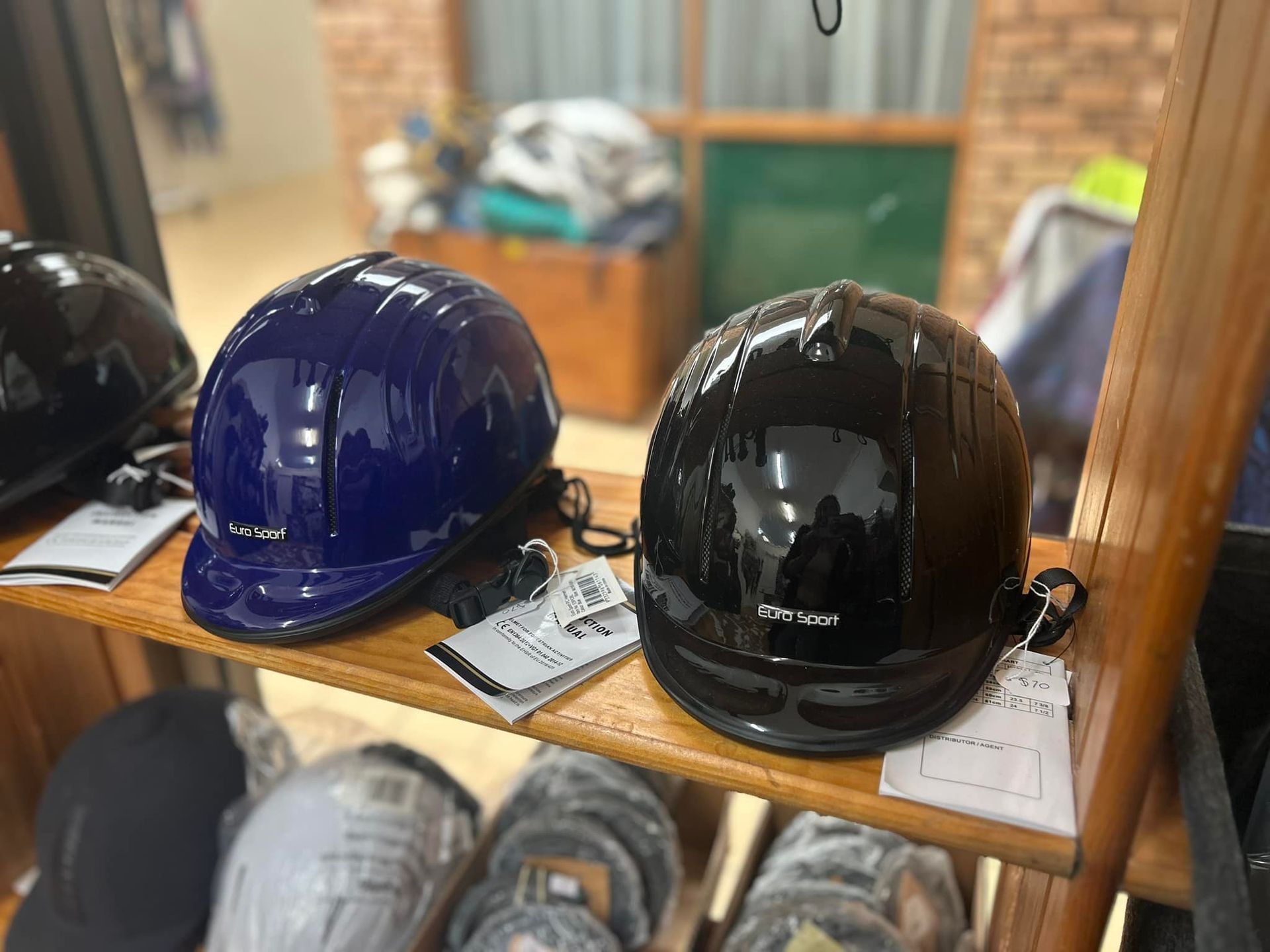 Two helmets are sitting on a wooden shelf in a store. — Paint Horse Saddlery In Taree, NSW