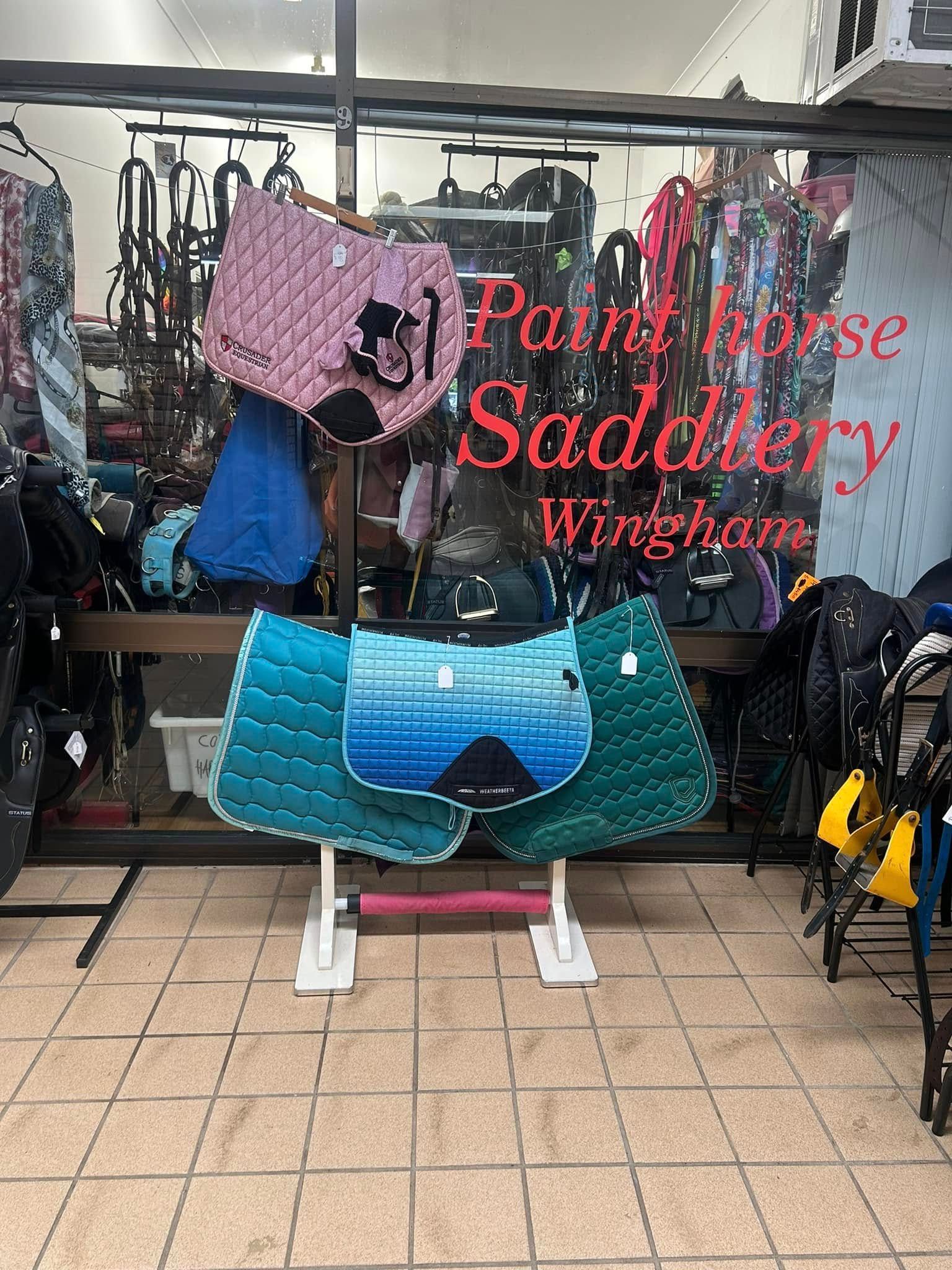 A bunch of saddle pads are sitting in front of a store window. — Paint Horse Saddlery In Taree, NSW