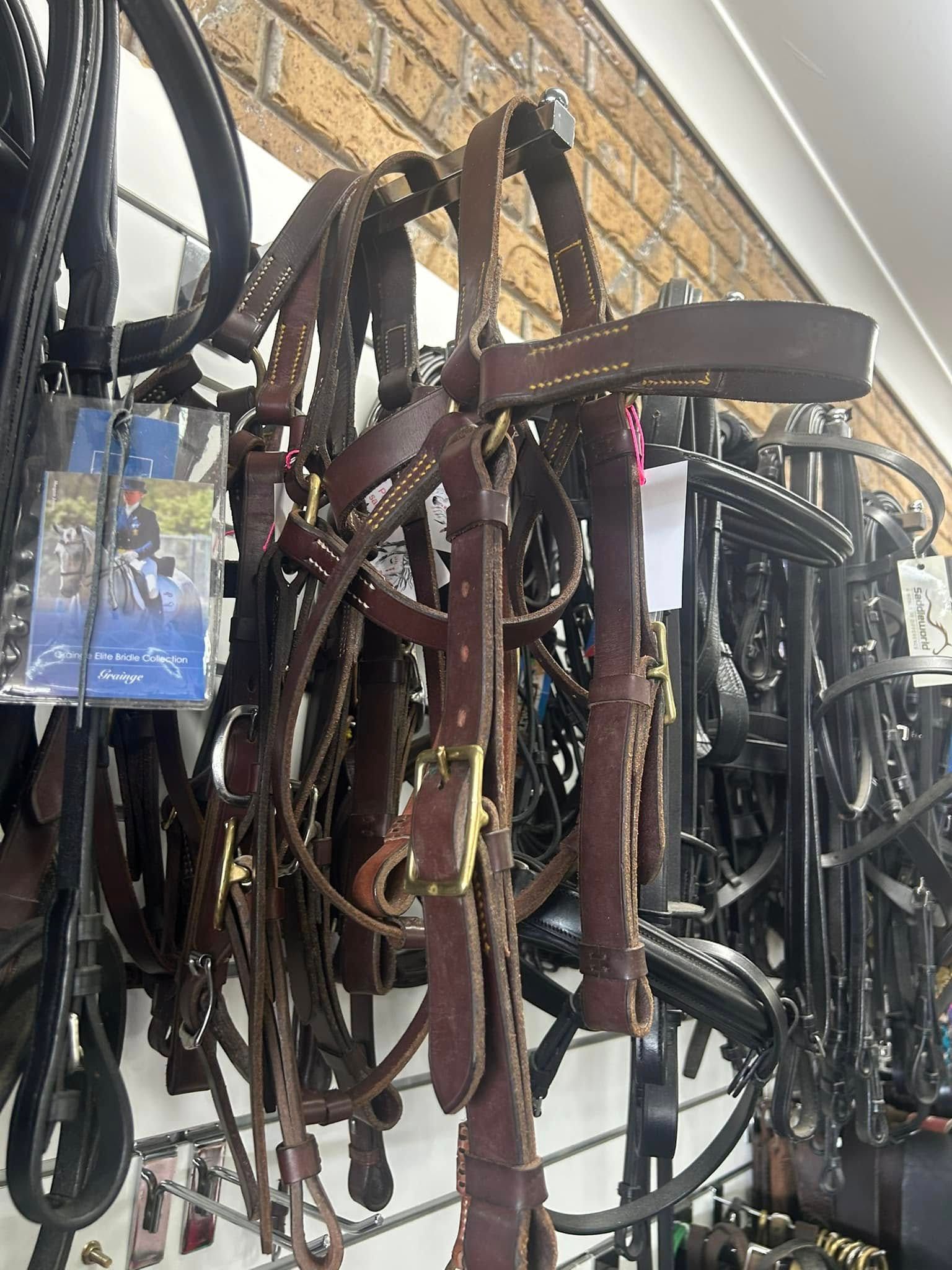 A bunch of brown leather bridles are hanging on a wall in a store. — Paint Horse Saddlery In Taree, NSW