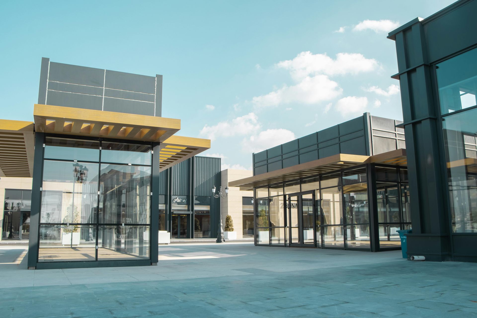 Modern glass buildings and canopies in a bright open plaza under a blue sky