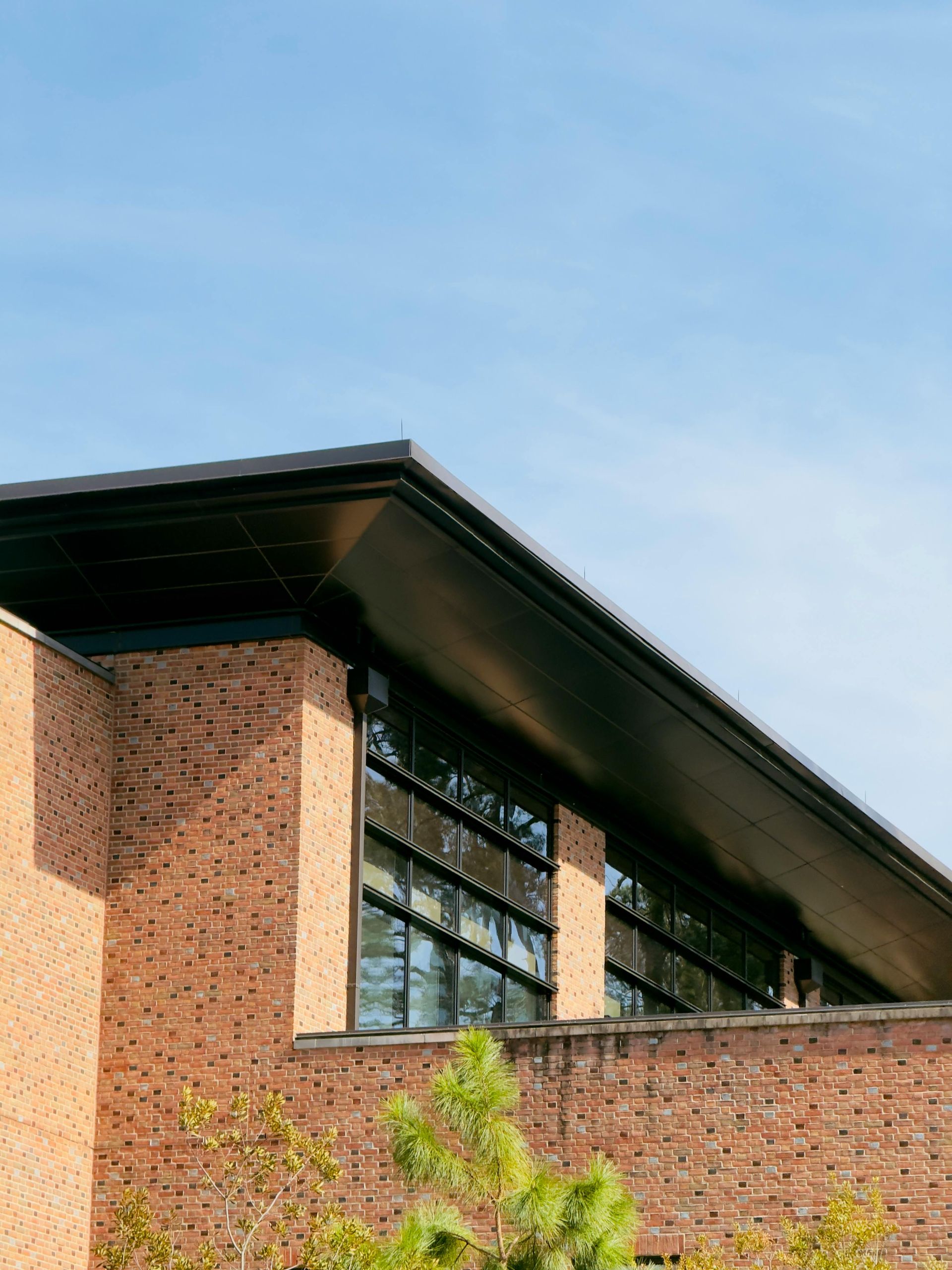 Brick building with large slanted roof and windows against a blue sky