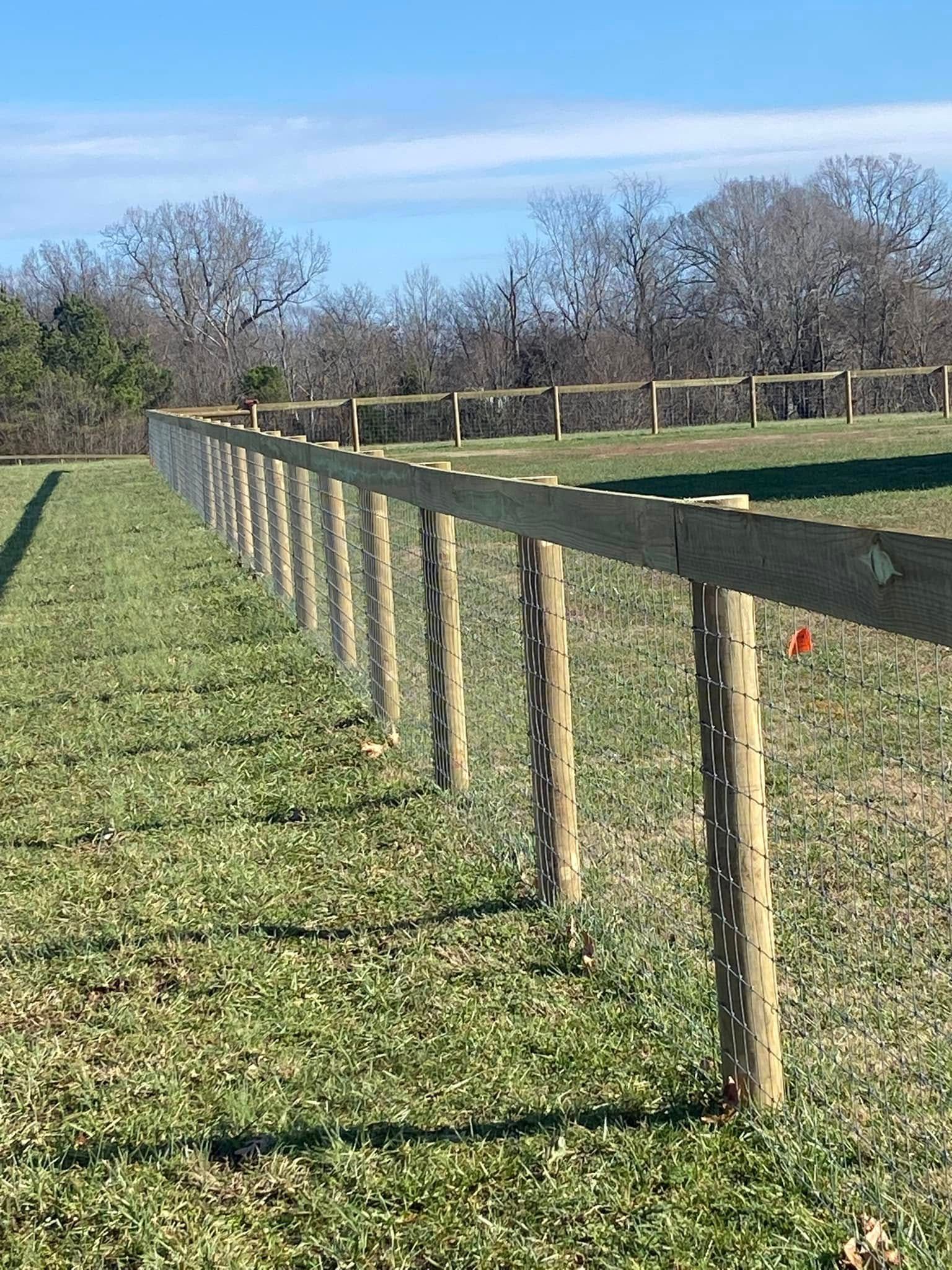 Wooden fence in a grassy field on a sunny day.