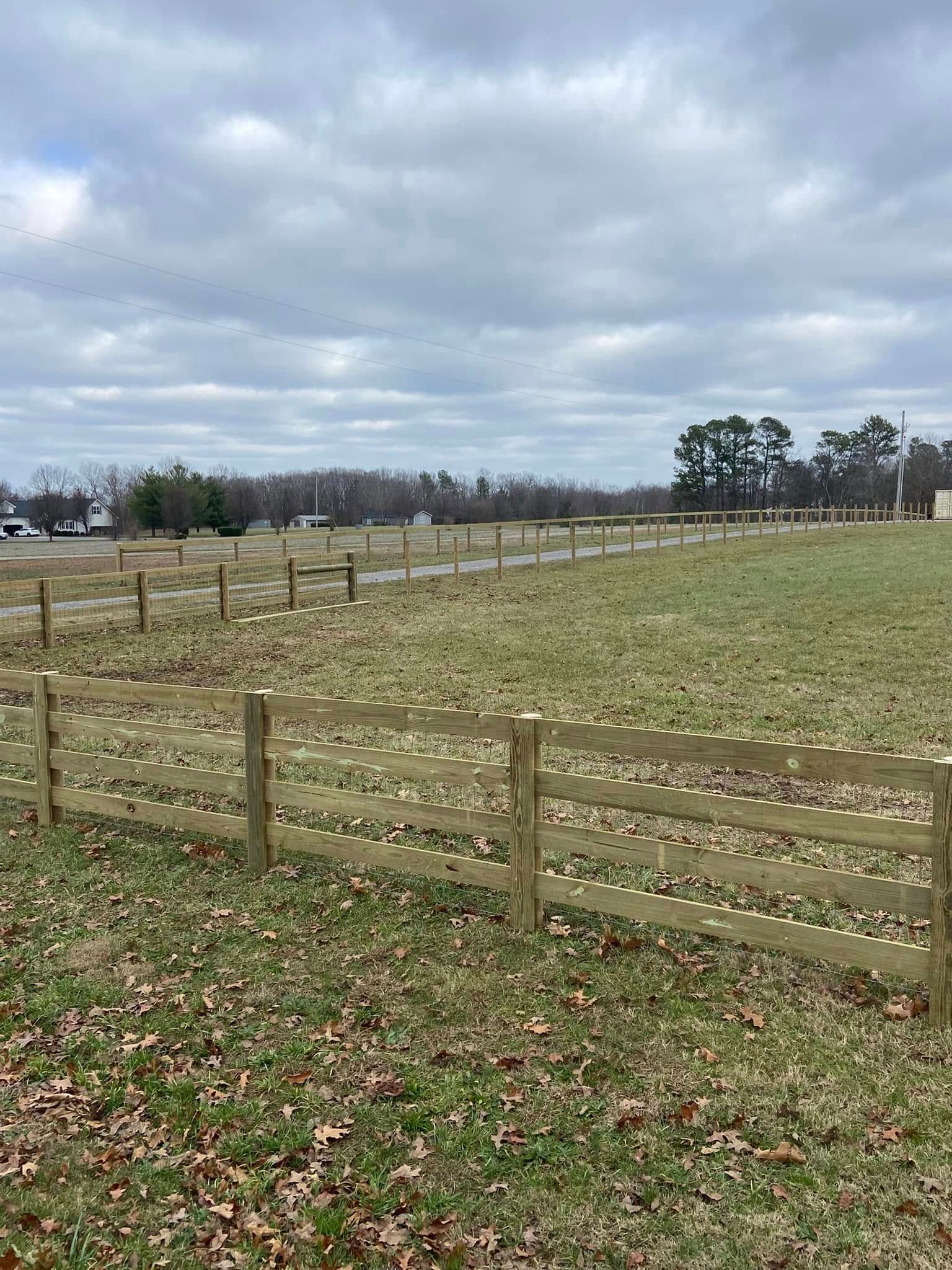 Wooden fence in a field under a cloudy sky.