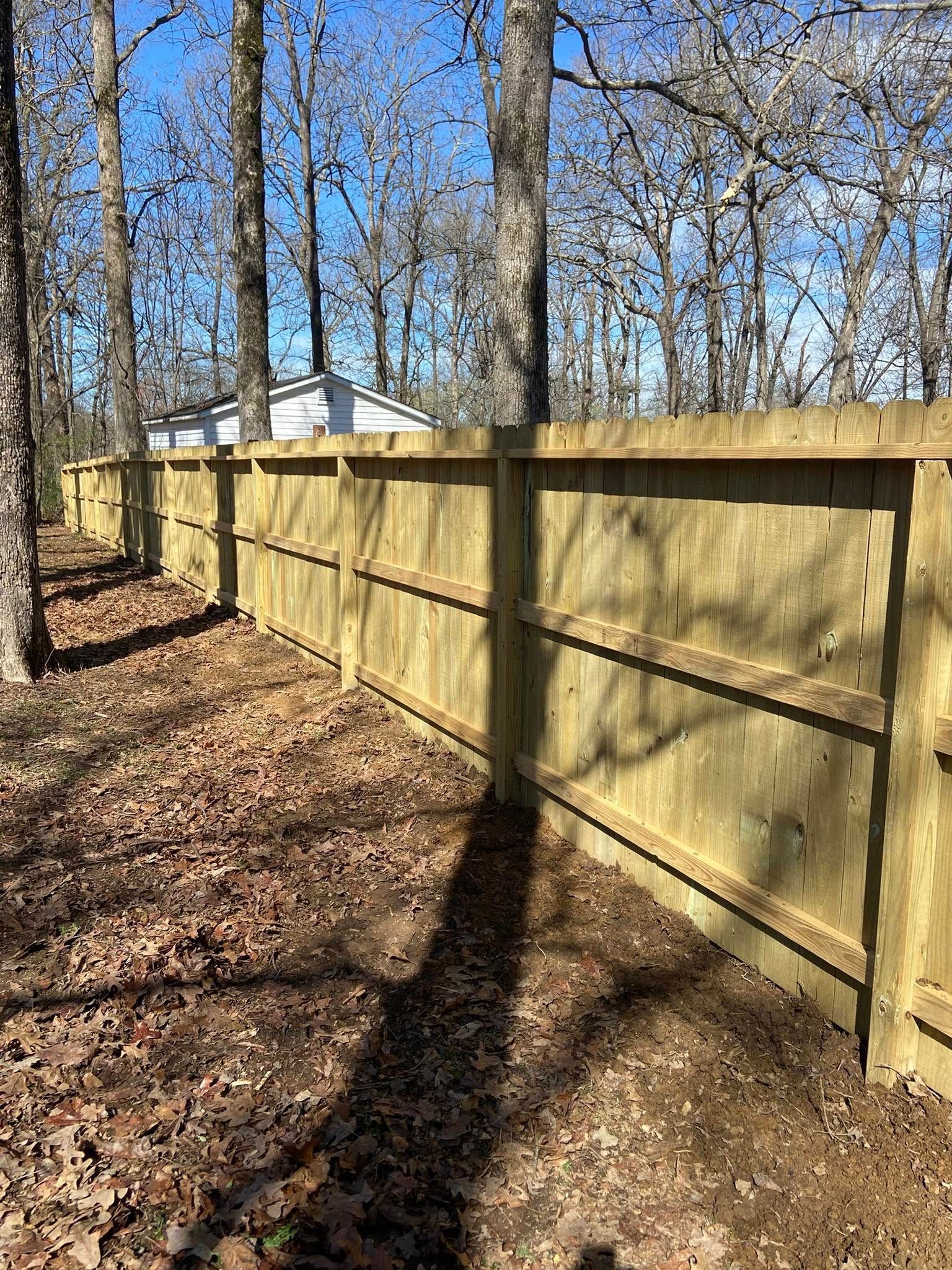 Wooden fence in a wooded area; sunny day.