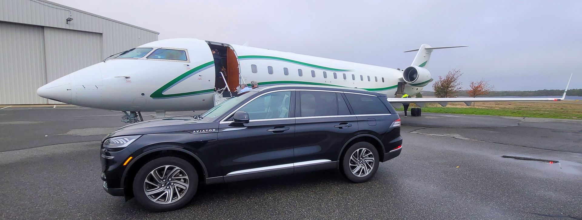 A car is parked in front of a private jet.