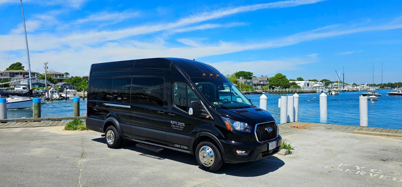 A black van is parked in front of a body of water.
