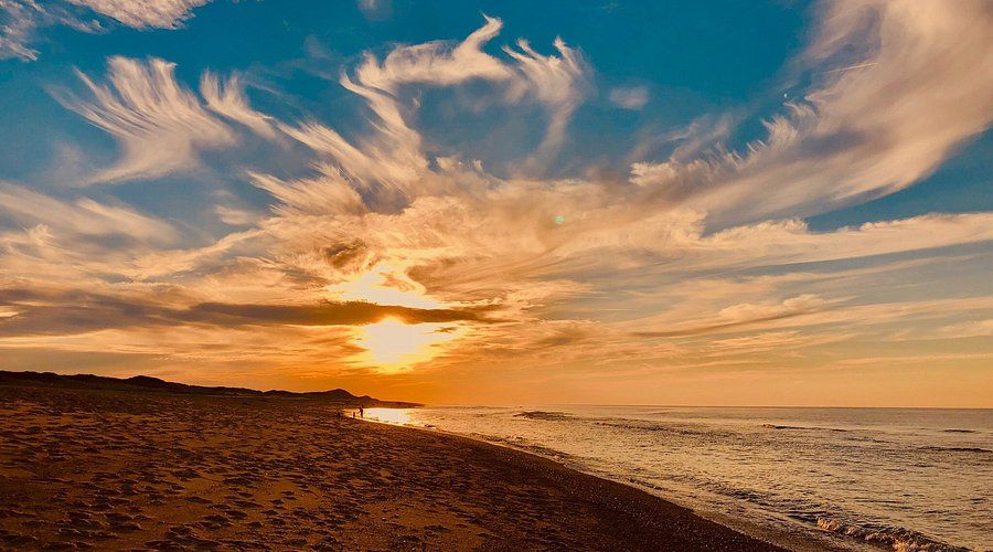 A sunset over a beach with a cloudy sky