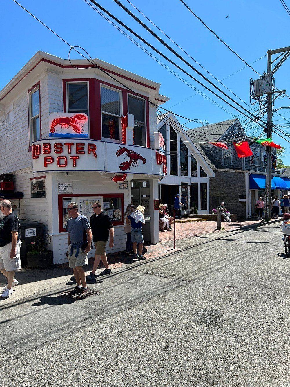 A group of people are walking in front of a lobster pot restaurant