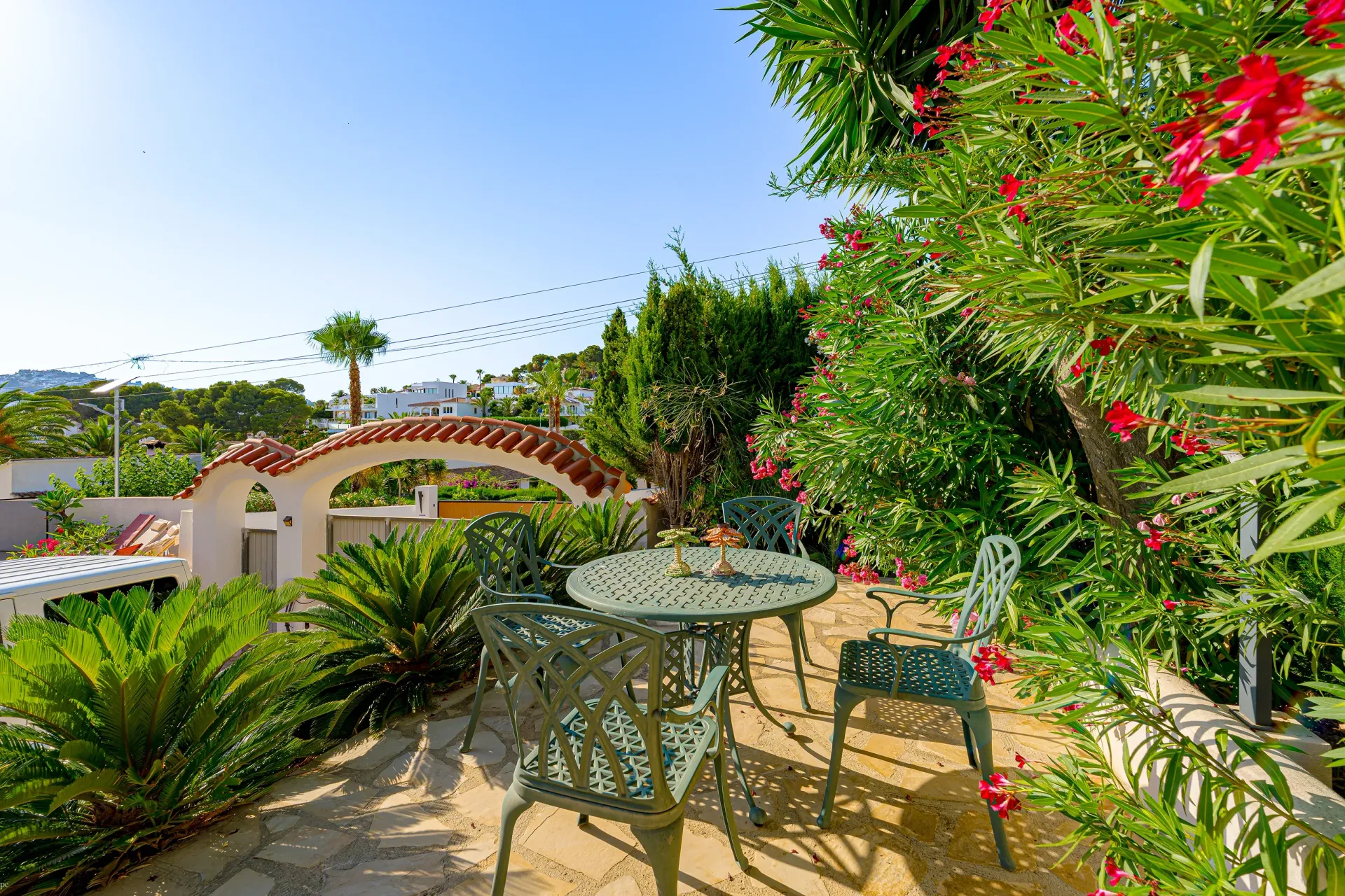 Mediterrane tuin van Villa Fio met sfeervol zitje, bloeiende planten en uitzicht over Moraira.