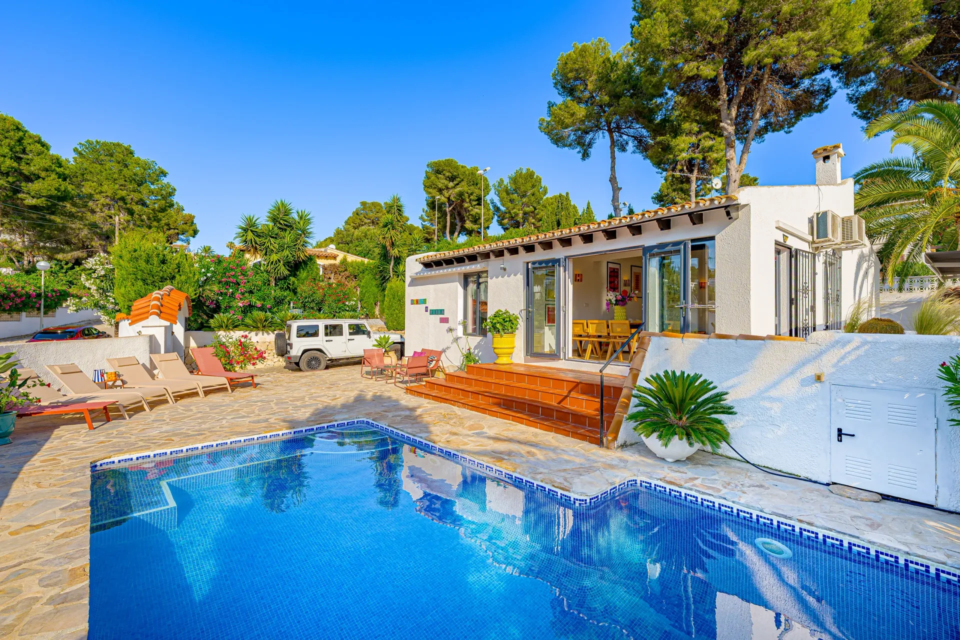 Verwarmd zwembad met houten terras en ligbedden bij Villa Fio in Moraira