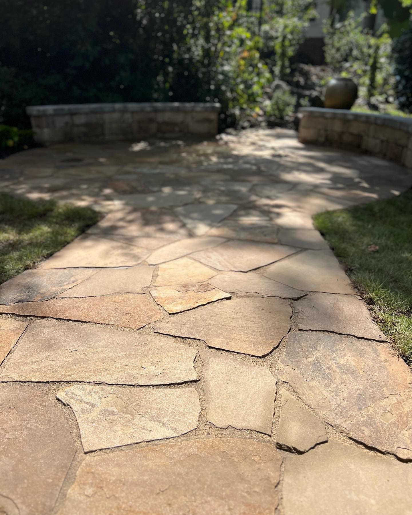 Flagstone walkway leading to stone benches in a garden.