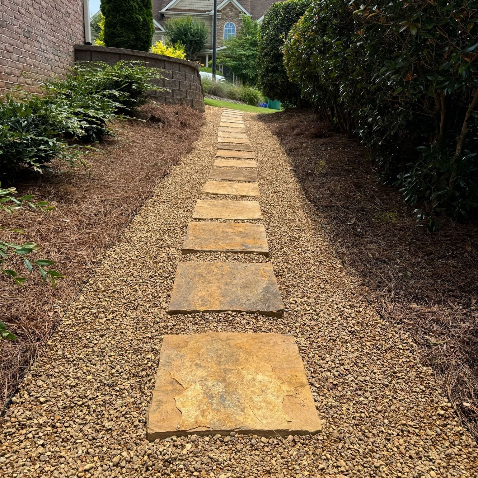 Stone path lined with gravel and greenery leads uphill.