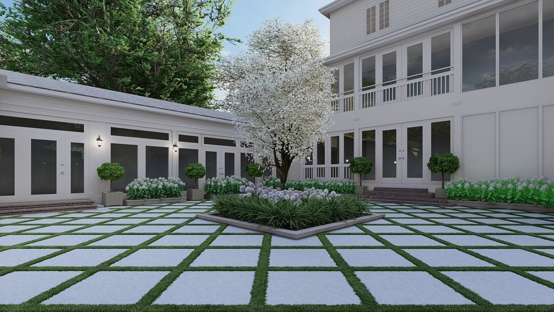 Courtyard with a large tree, paving stones, and a white house with large windows.