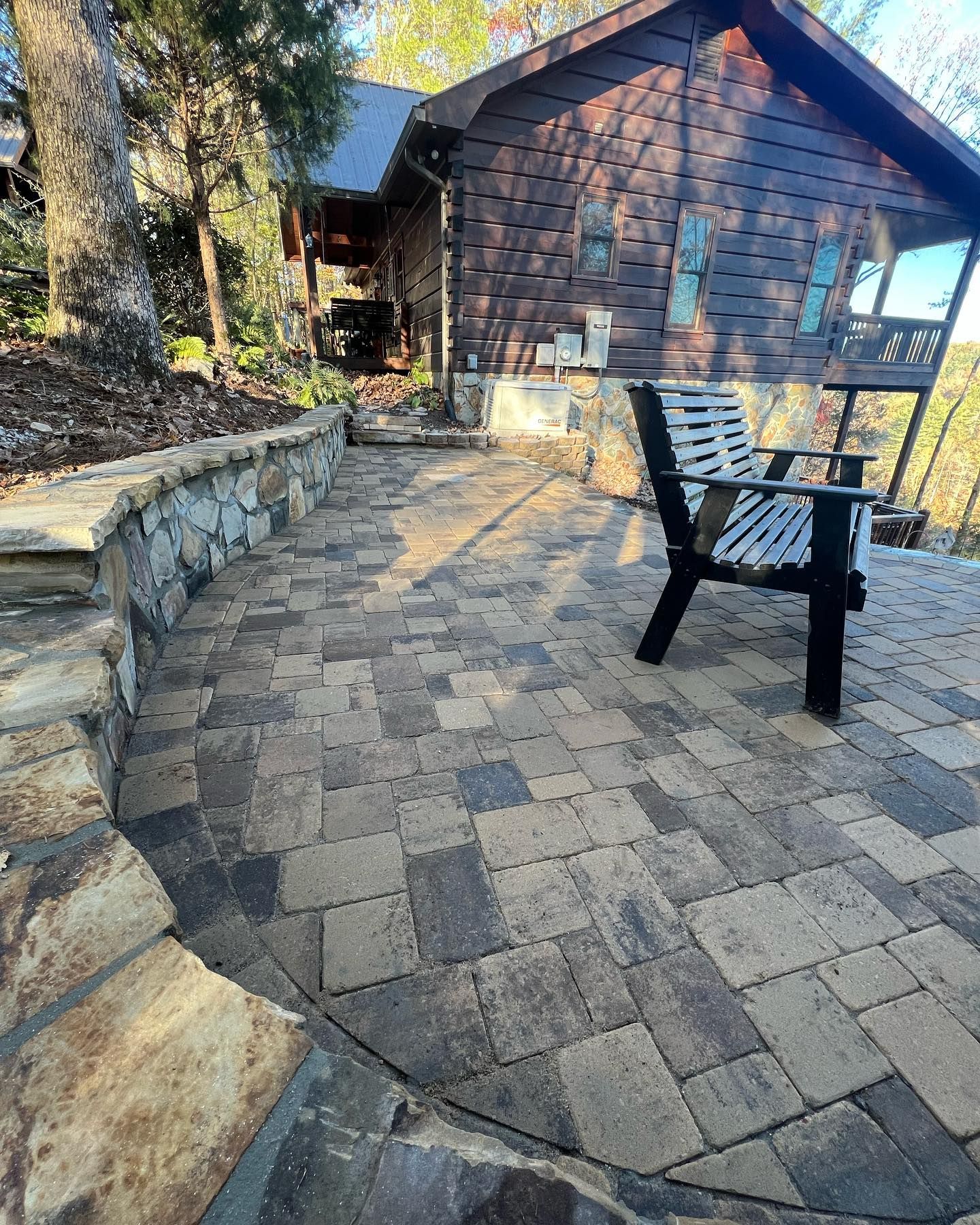 Stone patio with chair in front of a cabin.