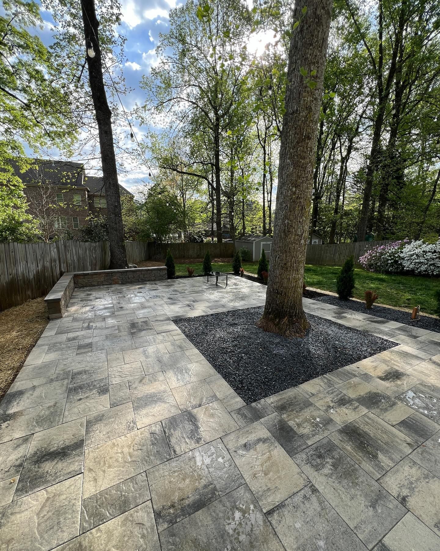 A patio with a tree in the middle of it and trees in the background.