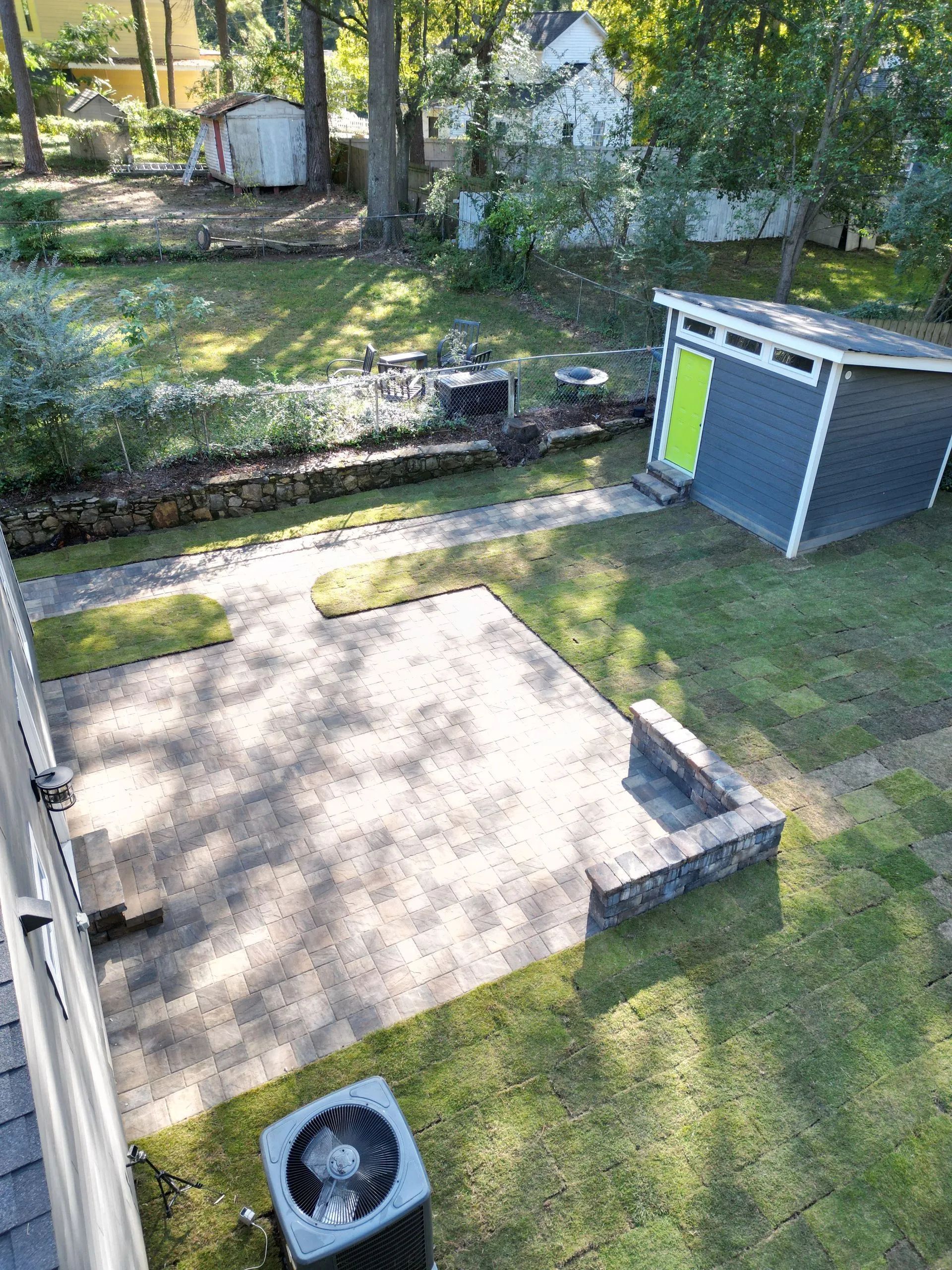 Backyard with patio, shed with green door, and air conditioning unit.