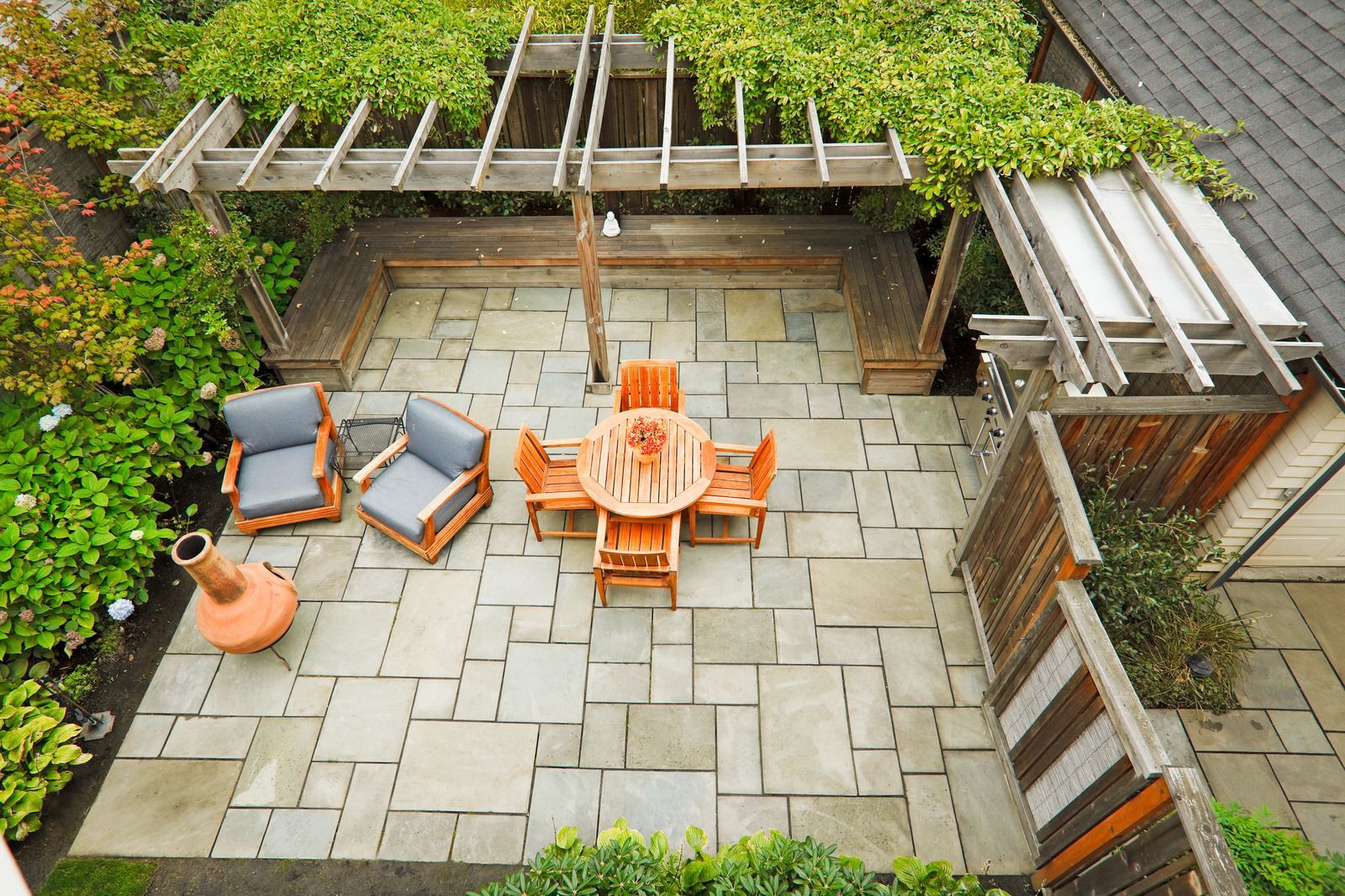An aerial view of a patio with a table and chairs under a pergola.