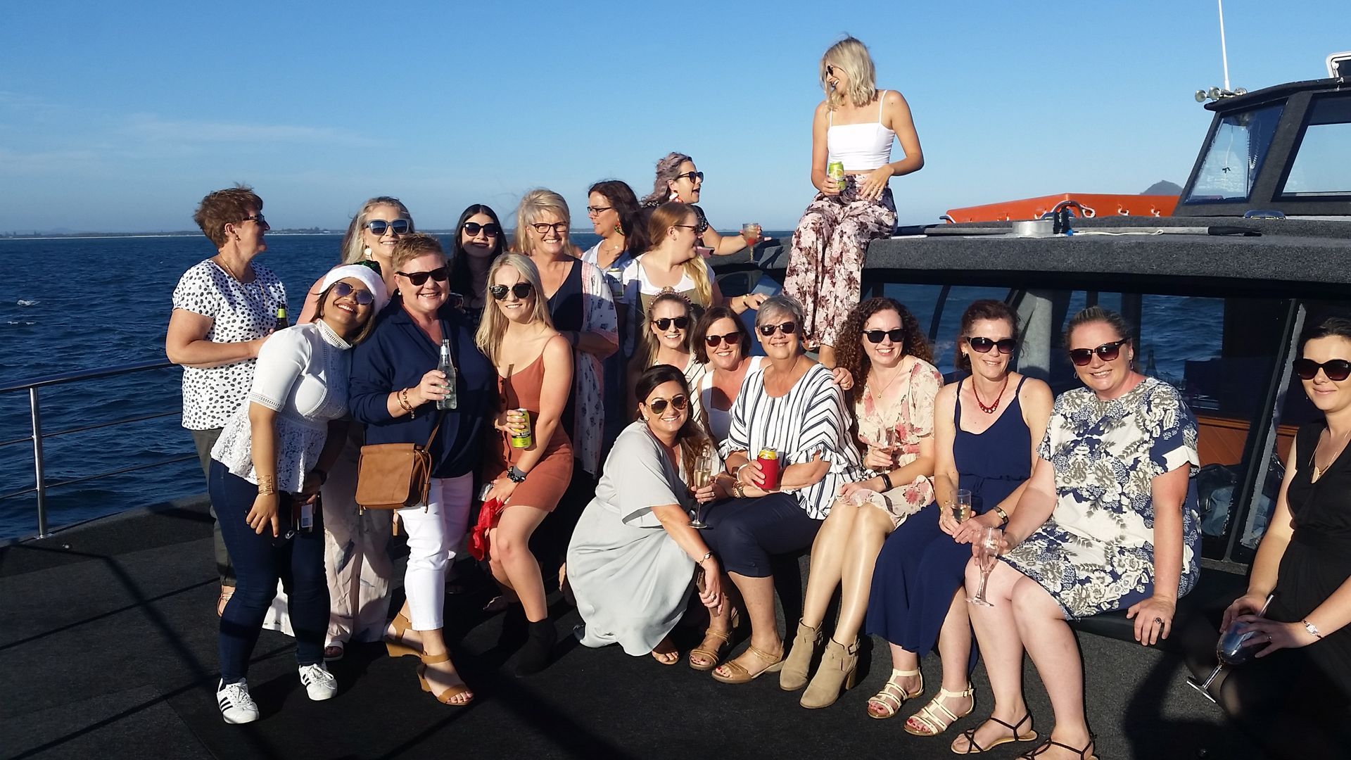 A Group of Women Smiles on A Boat Deck at Sea, Under a Blue Sky, Some Holding Drinks — YKnot Cruises in Nelson Bay, NSW