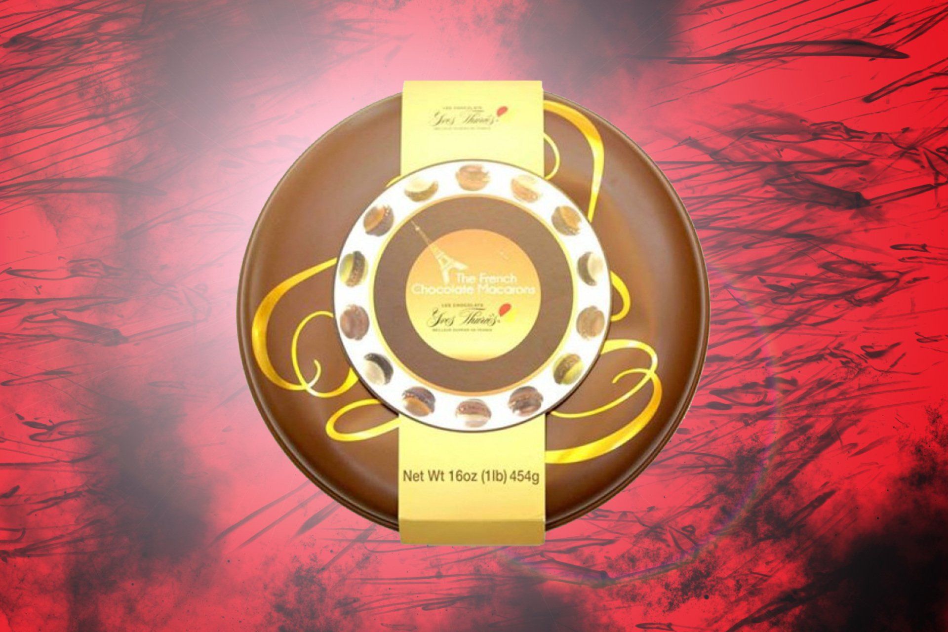 Round chocolate box with gold accents and a see-through center, on a red background.